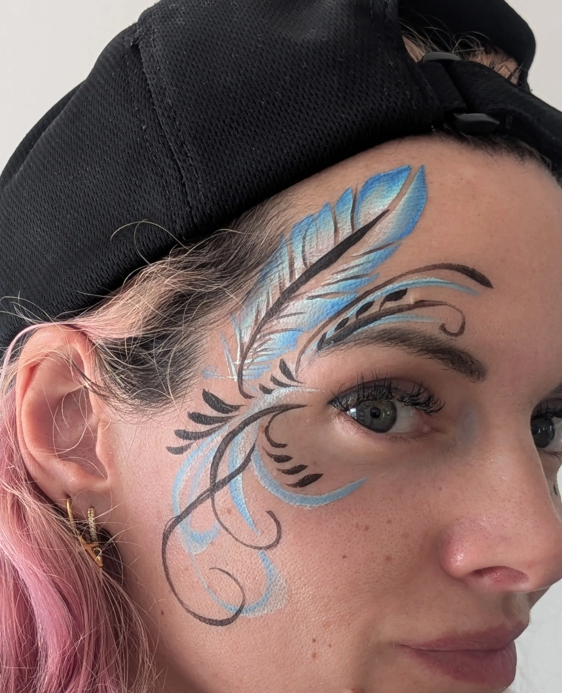 Maquillage artistique bleu et noir en grandes plumes graphiques autour de l&rsquo;&oelig;il